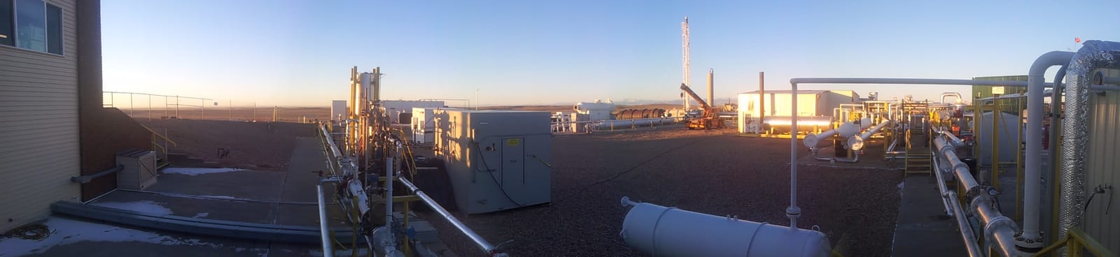 Panorama of the CEESI flow test station at first light: process piping, pressure vessels and control cabinets spread across open ground.